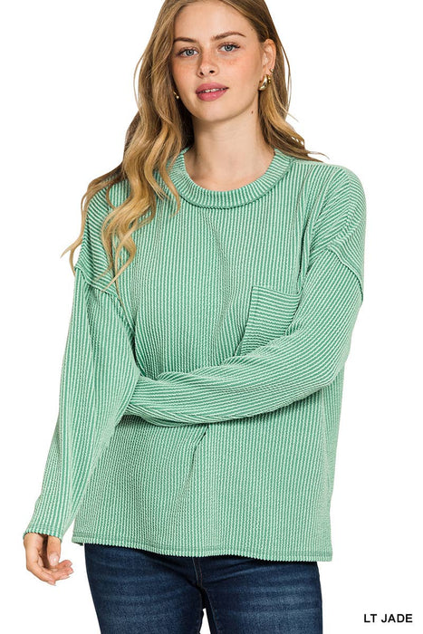 Woman wearing a light jade green sweater with a plain background