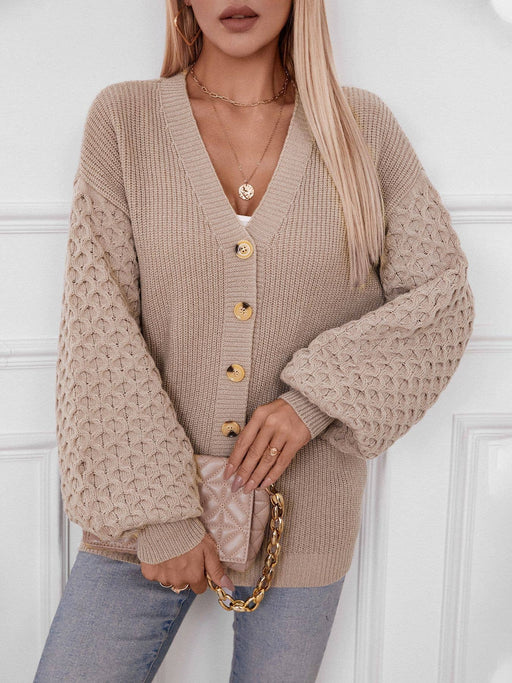 Person wearing a beige knitted cardigan with gold buttons against a white background