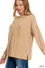 Woman wearing a beige ribbed sweater with a pocket on a white background