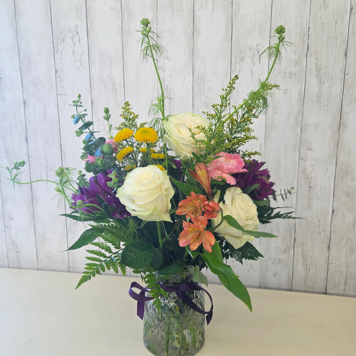 Colorful fresh flower bouquet featuring purples, pinks, whites, yellow, orange, and greenery from Heartland Store Minnesota