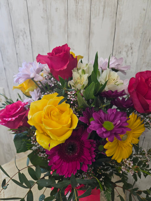Fresh flower arrangement in vase with yellow, purple, and lavender blooms and eucalyptus from Heartland Store MN
